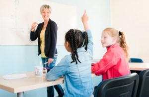 Zwei Schüler in einer Unterrichtssituation. Eine meldet sich, die Lehrerinzeigt ihr den Lösungsweg an der Tafel. Beim Duo-Kurs der Nachhilfe Radebeul.